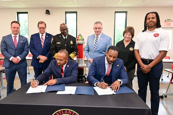 Atlanta Fire Capt. Alvin Rashad, president of the local firefighters' union, signs a collective bargaining agreement alongside Mayor Andre Dickens on Monday afternoon. (Courtesy of Joshua Spruiel, city of Atlanta, Mayor’s Office of Communications)