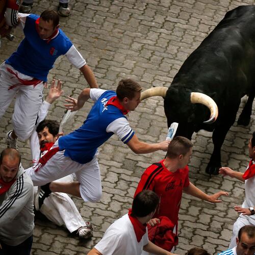 FILE - U.S. runner Bill Hillmann, 35, from Chicago, center left, falls seconds before a Victoriano del Rio ranch fighting bull gored him on his right leg during the running of the bulls of the San Fermin festival, in Pamplona, Spain, Wednesday, July 9, 2014. (AP Photo/Daniel Ochoa de Olza, File)