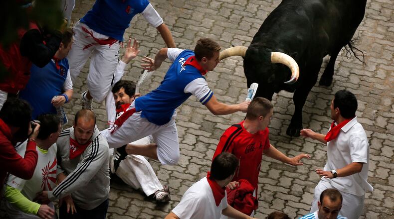 FILE - U.S. runner Bill Hillmann, 35, from Chicago, center left, falls seconds before a Victoriano del Rio ranch fighting bull gored him on his right leg during the running of the bulls of the San Fermin festival, in Pamplona, Spain, Wednesday, July 9, 2014. (AP Photo/Daniel Ochoa de Olza, File)