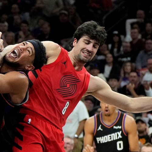Phoenix Suns guard Devin Booker (1) gets fouled by Portland Trail Blazers forward Deni Avdija (8) during the second half of an NBA play-in tournament basketball game, Tuesday, April 14, 2026, in Phoenix. (AP Photo/Ross D. Franklin)