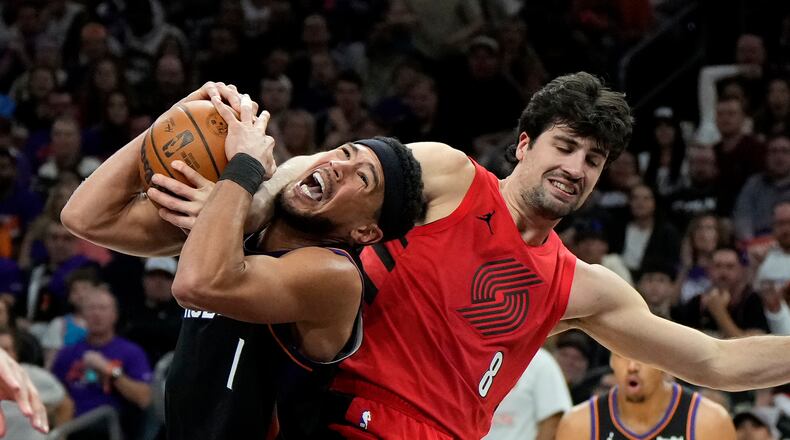 Phoenix Suns guard Devin Booker (1) gets fouled by Portland Trail Blazers forward Deni Avdija (8) during the second half of an NBA play-in tournament basketball game, Tuesday, April 14, 2026, in Phoenix. (AP Photo/Ross D. Franklin)