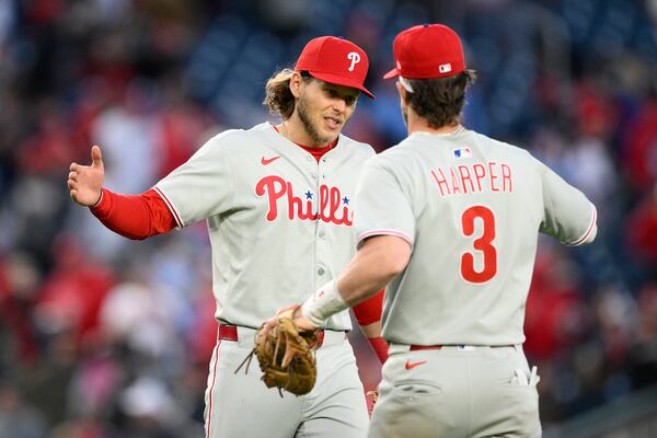 Philadelphia Phillies third baseman Alec Bohm, left, and first baseman Bryce Harper (3) celebrate after opening-day baseball game against the Washington Nationals, Thursday, March 27, 2025, in Washington. (AP Photo/Nick Wass)