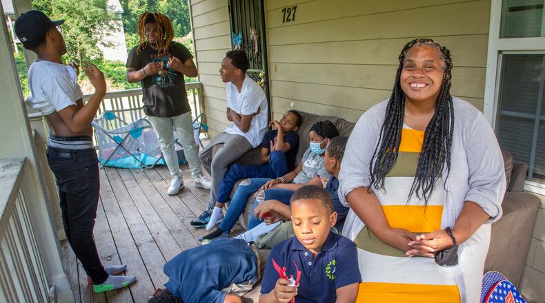 Tameka Stinson sits on the porch of her Atlanta home with her nine children, ages 7 to 19. While the affordable housing program covers her rent and electricity, an unexpected balance on her water bill put a strain on her finances, and she says that the child tax credit has helped pay for back-to-school items. “Kids always needs shoes, clothes, toiletries and stuff,’' Stinson said. (Steve Schaefer for The Atlanta Journal-Constitution)