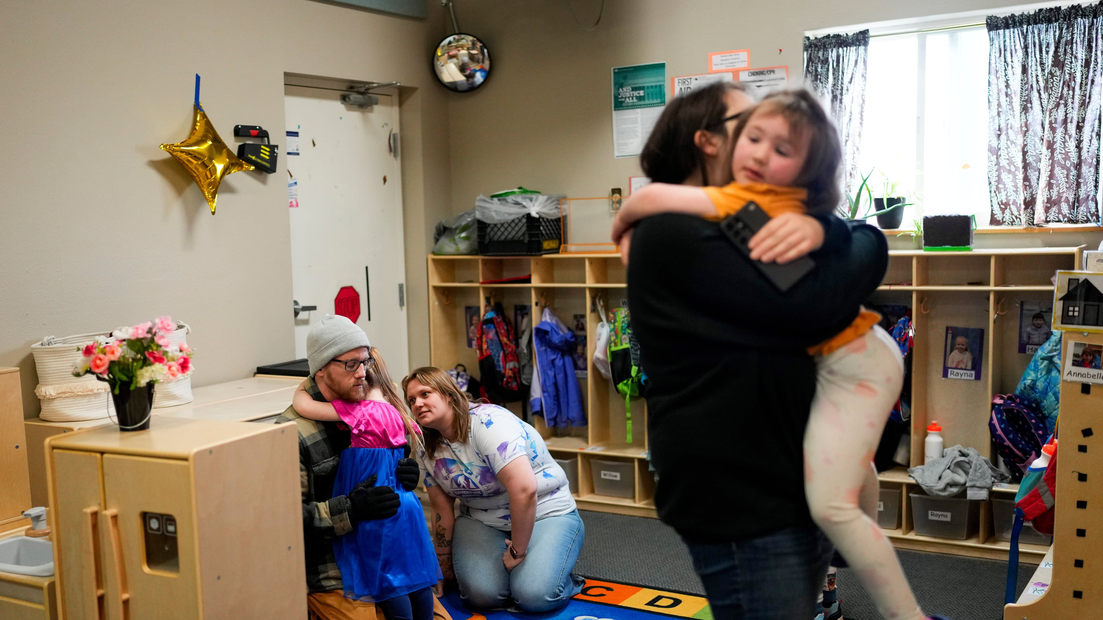 FILE - Olivia Starr clings to her father, Thaxter Hall, as Associate Educator Jessica Clark works to comfort her as she is dropped off for the last day of school at the Meadow Lakes CCS Early Learning, a Head Start center, May 8, 2024, in Wasilla, Alaska. (AP Photo/Lindsey Wasson, File)