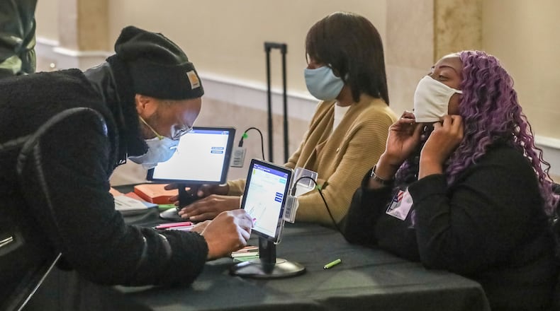 January 5, 2021 Atlanta: Kamal Gillespie (left) verifies his voter I.D. information to poll workers Brandy Allen (center) and Cuedriene Edwards (right) on Tuesday, Jan. 5, 2021 at the Park Tavern located at 500 10th St NE in Atlanta. Georgia’s long moment in the national spotlight culminated Tuesday, Jan. 5, 2021, when state voters cast their votes to determine which party would control the U.S. Senate. Georgia voters also voted to elect a member of the state Public Service Commission, which regulates energy and utility rates and issues. The two most expensive Senate races in history saw more than $833 million been spent by the four campaigns and outside groups supporting them, blanketing the airwaves and stuffing mailboxes across the state. Much of that money has come from organizations with no direct connection to Georgia. (John Spink / John.Spink@ajc.com)