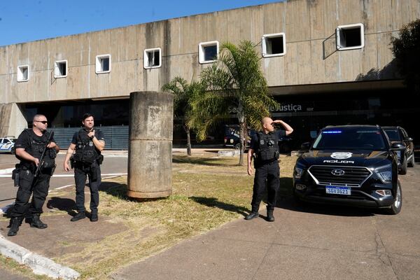 Federal police officers stand at the the Secretariat of Penitentiary Administration office where Brazil's former President Jair Bolsonaro, who is on trial for allegedly attempting to stage a coup, after he arrived to be fitted with an electronic ankle monitor in Brasilia, Brazil, Friday, July 18, 2025. (AP Photo/Eraldo Peres)
