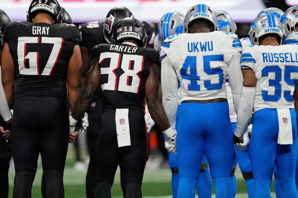 Atlanta Falcons and Detroit Lions players stand on the field hand-in-hand after Lions safety Morice Norris was injured during the second half Friday.