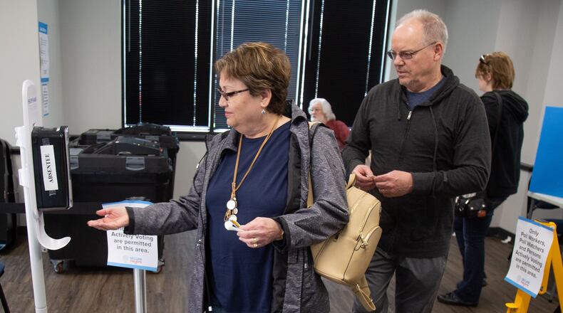 Sheri and James Marshall sanitize their hands after voting at the Marietta polling station during Saturday’s early voting on March 14, 2020. STEVE SCHAEFER / SPECIAL TO THE AJC