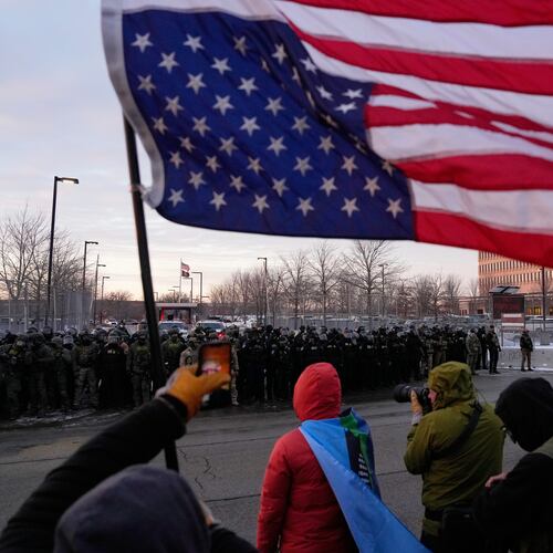 A person holds an upside-down American flag as law enforcement stand during a protest outside the Bishop Henry Whipple Federal Building on Saturday, Jan. 17, 2026, in Minneapolis. (AP Photo/Yuki Iwamura)