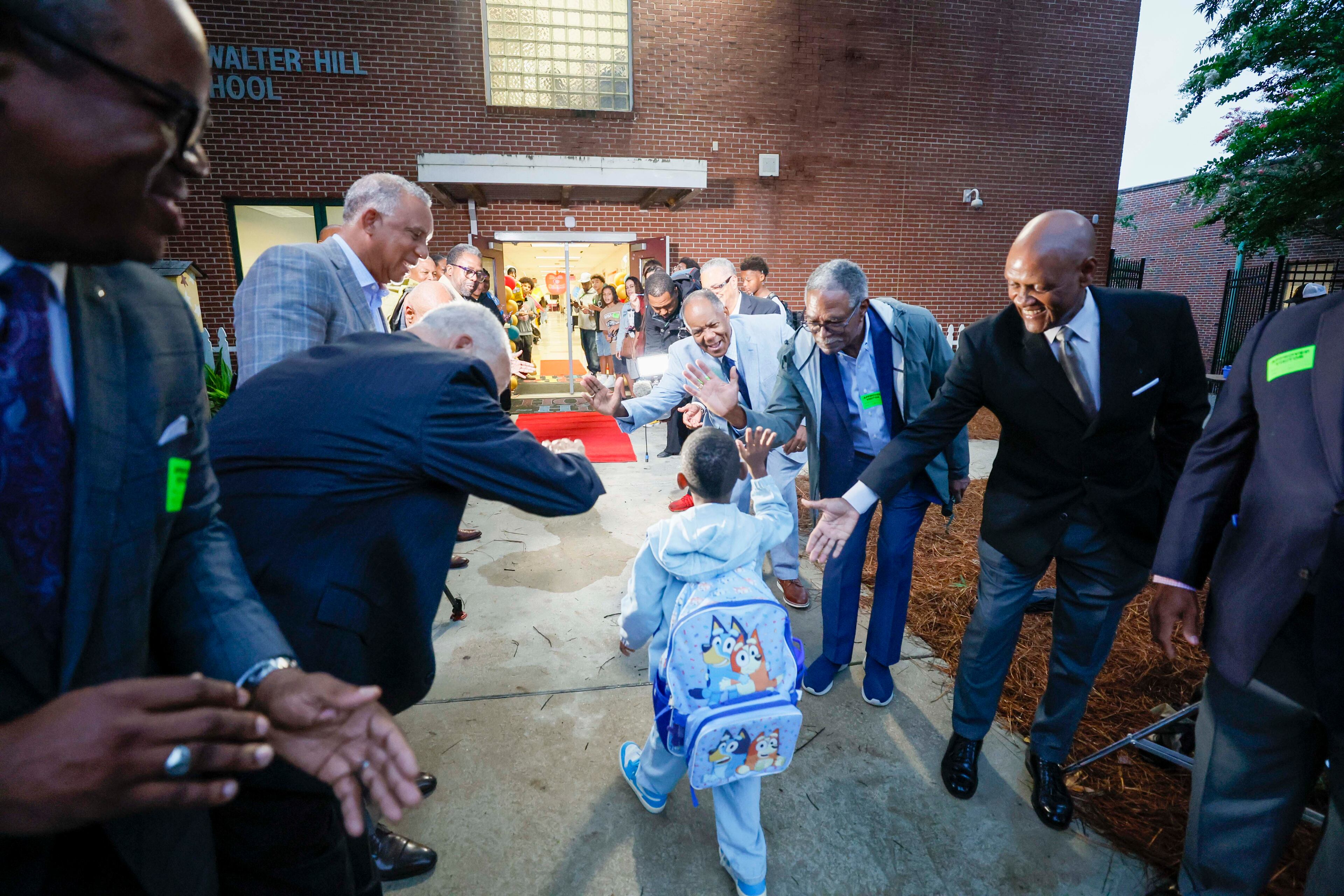 Members of Kappa-Boulé Atlanta are about the high fives as they greet students on the first day of classes at Hope-Hill Elementary School. (Miguel Martinez/AJC)
