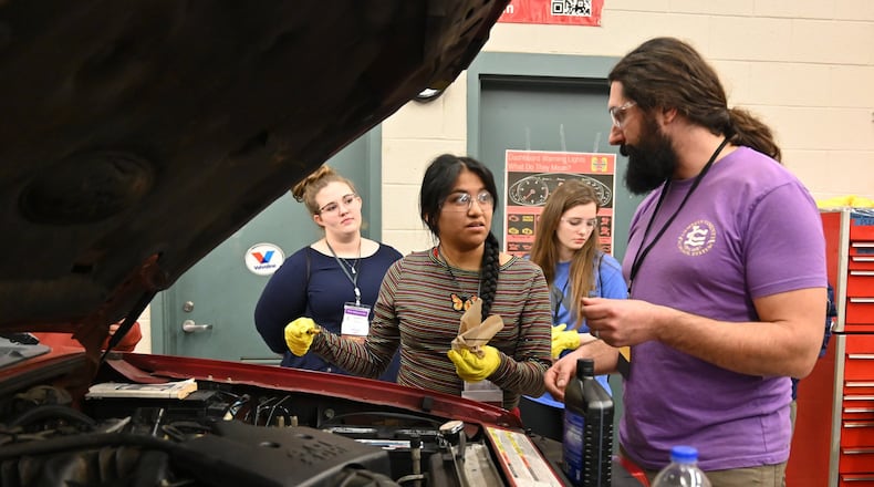 Instructor Jesse Perethian (right) helps senior Erica Ramirez (center) check engine oil during the second annual Senior Adulting Day at Lumpkin County High School in Dahlonega on Friday, Jan. 24, 2020.