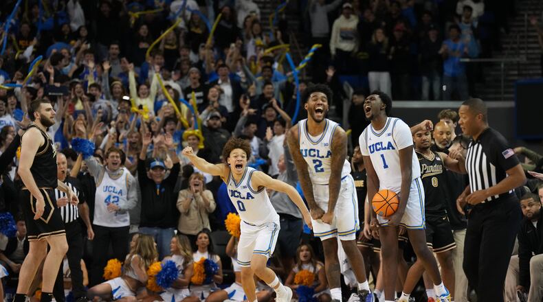 UCLA's Trent Perry (0), Donovan Dent (2) and Xavier Booker (1) celebrate after defeating Purdue in an NCAA college basketball game in Los Angeles, Tuesday, Jan. 20, 2026. (AP Photo/Jae C. Hong)