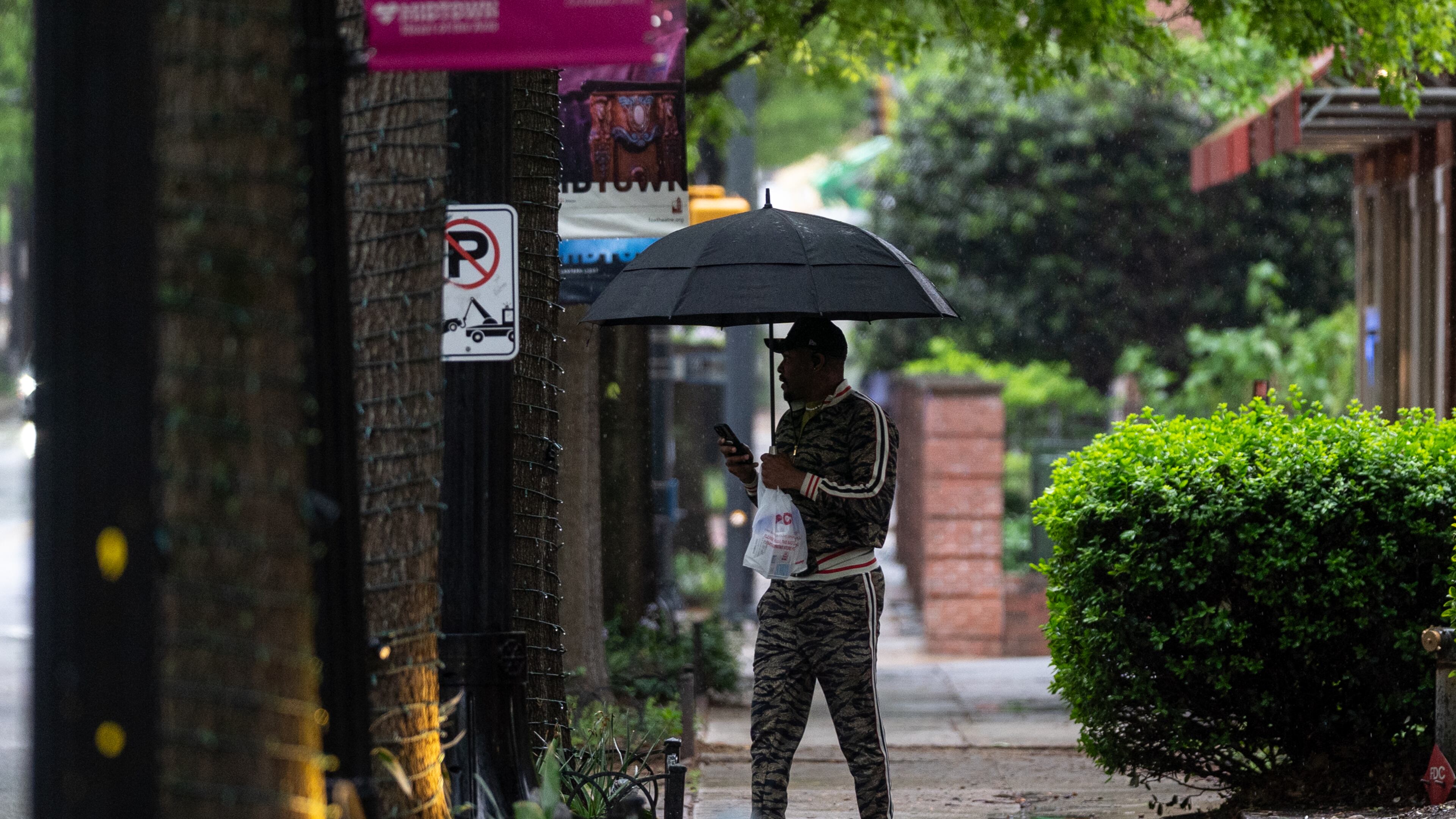 A man with an umbrella walks along Peachtree Street in downtown Atlanta. Storms are hitting the state again this weekend. (Ben Hendren for the AJC)