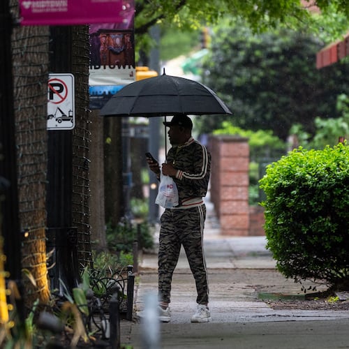 A man with an umbrella walks along Peachtree Street in downtown Atlanta. Storms are hitting the state again this weekend. (Ben Hendren for the AJC)