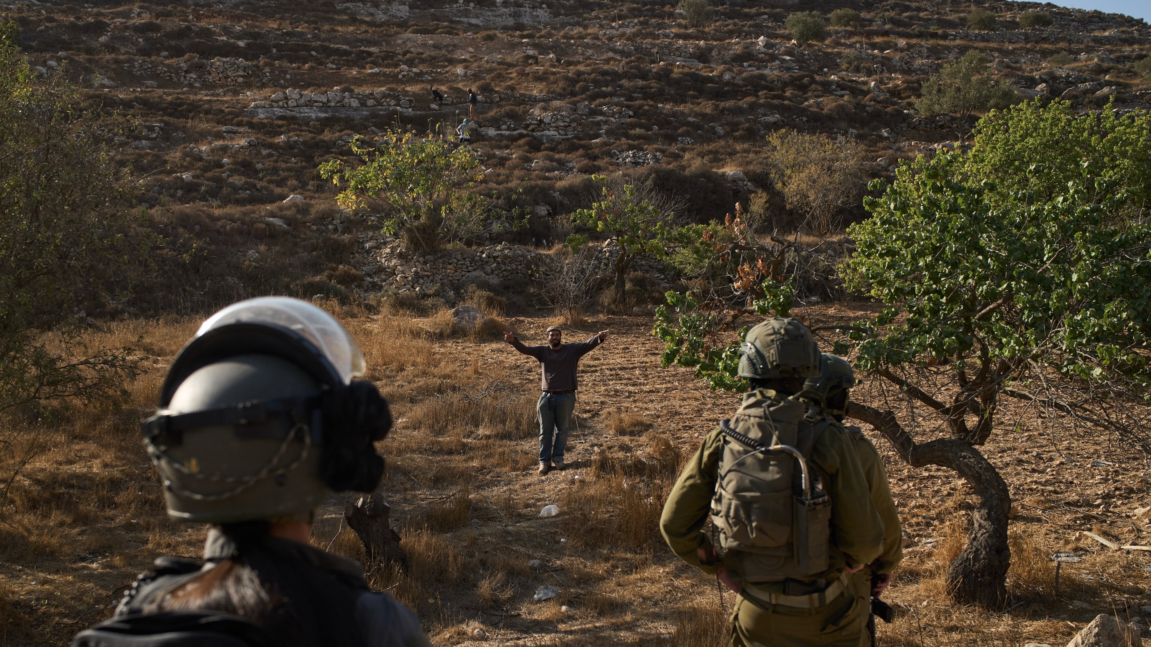 An Israeli settler gestures as Israeli soldiers block access for Palestinians to an area for harvesting olives in the West Bank village of Sa'ir, near Hebron, Thursday, Oct. 23, 2025. (AP Photo/Leo Correa)