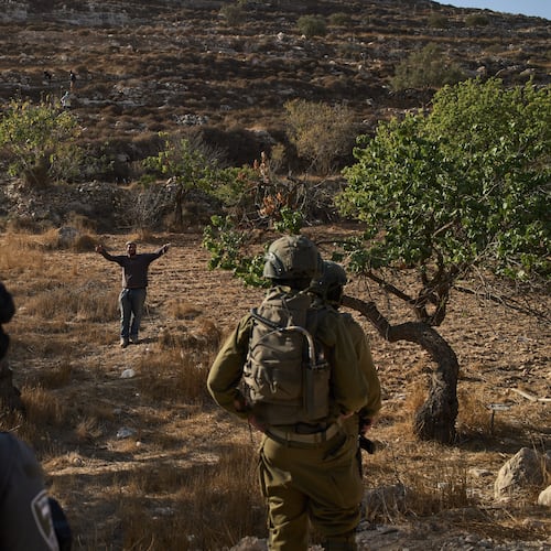 An Israeli settler gestures as Israeli soldiers block access for Palestinians to an area for harvesting olives in the West Bank village of Sa'ir, near Hebron, Thursday, Oct. 23, 2025. (AP Photo/Leo Correa)