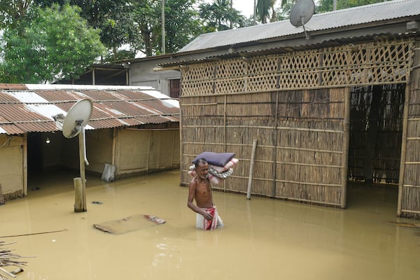 FILE - A villager wades through floodwaters to reach safer places after days of torrential monsoon rains in Kampur in India's northeastern state of Assam, June 2, 2025. (AP Photo, File)