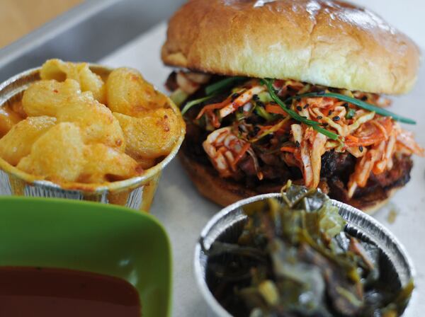 Heirloom Market BBQ’s spicy Korean pork sandwich (shown with collard greens and mac & cheese). Becky Stein/For the AJC)