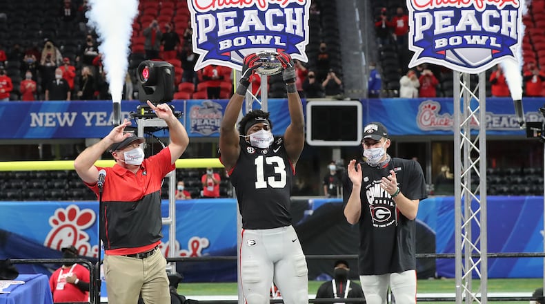 010121 ATLANTA: Georgia head coach Kirby Smart (from left), defensive player of the game Azeez Ojulari hoisting the trophy, and quarterback JT Daniels celebrate beating Cincinnati 24-21 in the NCAA college football Peach Bowl game on Friday, Jan. 1, 2021, in Atlanta.   Curtis Compton / Curtis.Compton@ajc.com”