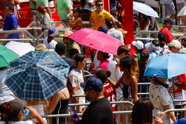 People used umbrellas to escape the heat at the FIFA Fan Festival in early July. (Arvin Temkar/AJC)