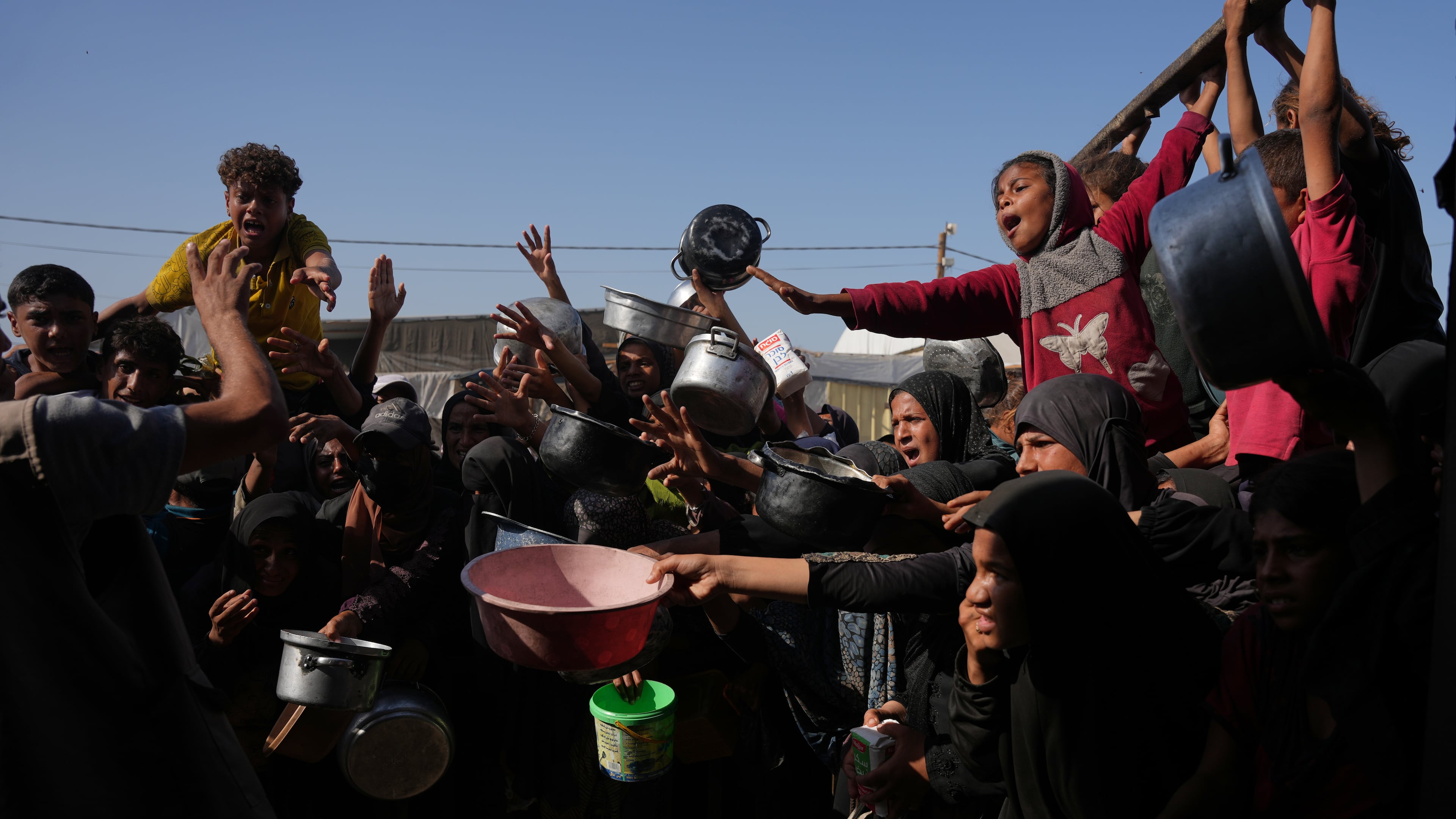 Palestinians wait to get donated sugar and rice at a community kitchen in Khan Younis, southern Gaza Strip, Friday, Oct. 31, 2025. (AP Photo/Abdel Kareem Hana)