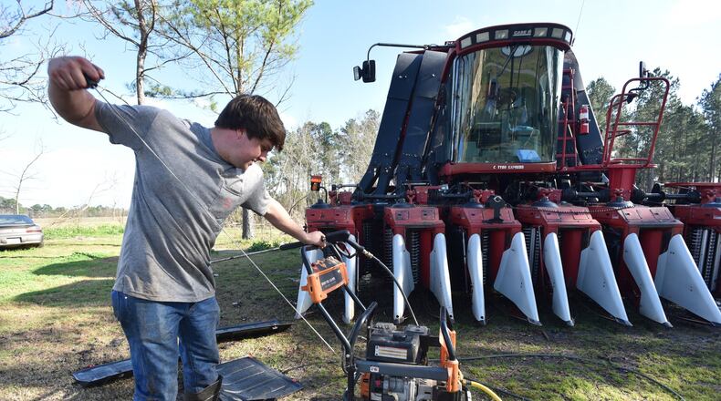 Young farmer Reese Foster prepares to power-wash a gigantic cotton picker earlier this year at his home near Dawson, Georgia. Foster and many other farmers are carrying over debt into 2019 because bad weather ruined crops. Chinese tariffs are also destabilizing the market for cotton, pecans, peanuts and other Georgia crops, which has a broader economic impact on the state. HYOSUB SHIN / HSHIN@AJC.COM