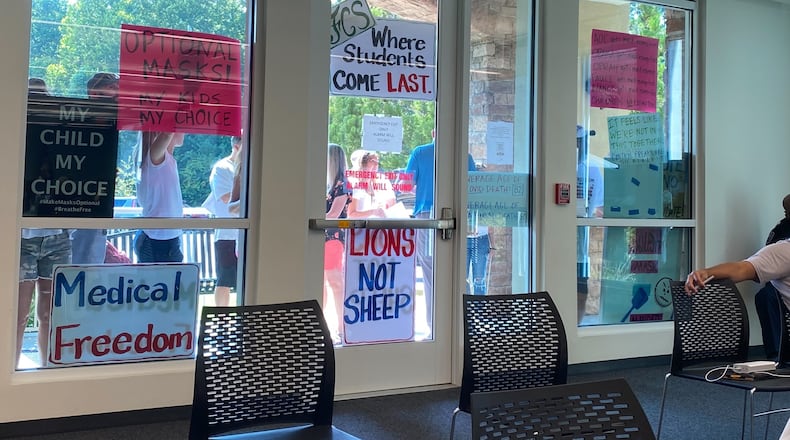Protesters opposed to Fulton County Schools' mask requirement hold up signs outside of the school board's meeting last August. This month, masks will once again be required in all buildings through Jan. 21. Vanessa McCray / AJC file photo)