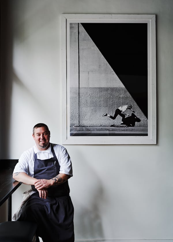 Chef Terry Koval in his restaurant, the Deer and the Dove, standing in front of a skating image by Grant Brittain. (Courtesy of Andrew Thomas Lee)