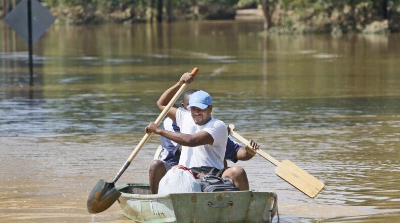 Earl Knight uses a shovel as an oar as rows down the still flooded Oglesby Road in Powder Springs with Cornell Daniels in September 2009. Bob Andres, bandres@ajc.com