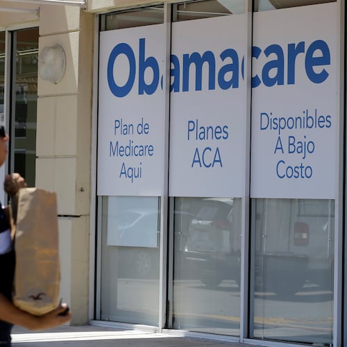 FILE - A man walks by an healthcare insurance office in Hialeah, Fla., July 27, 2017, (AP Photo/Alan Diaz, File)