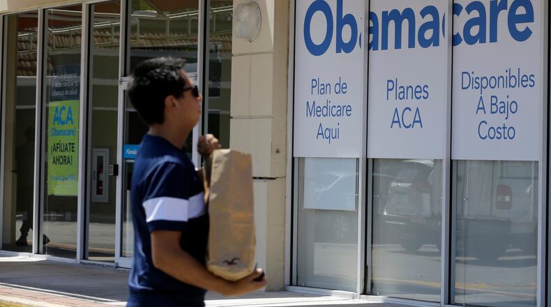 FILE - A man walks by an healthcare insurance office in Hialeah, Fla., July 27, 2017, (AP Photo/Alan Diaz, File)