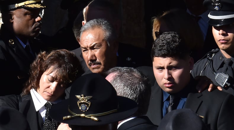 December 18, 2018 Dunwoody - Family members of officer Edgar Isidro Flores react as the casket of officer Edgar Isidro Flores is brought out at All Saints Catholic Church in Dunwoody on Tuesday, December 18, 2018. Flores was shot and killed in DeKalb County in the line of duty last week. HYOSUB SHIN / HSHIN@AJC.COM