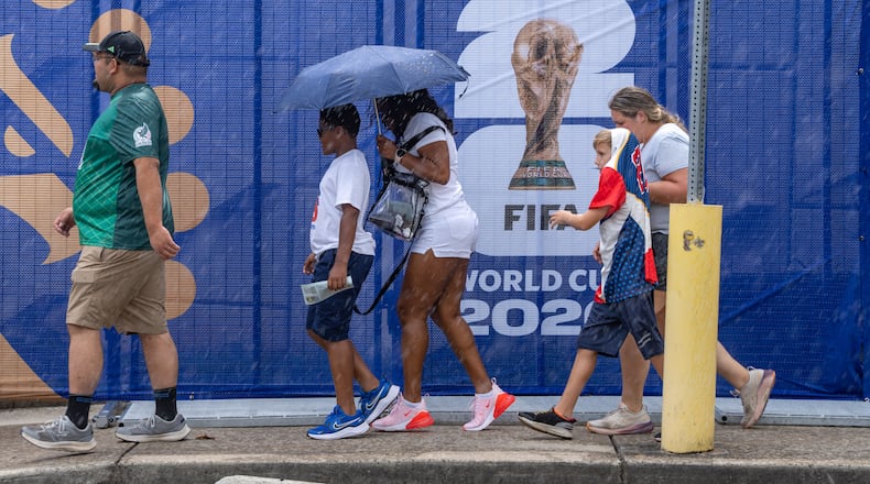 Soccer fans walk in the rain to Atlanta Stadium for the South Africa vs. Czechia match on Thursday. (Ben Hendren for the AJC)