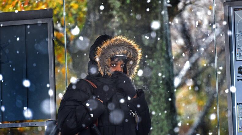 A lady covers her face at a Marta bus station as a wintry mix of sleet and snow is falling in East Atlanta Village. HYOSUB SHIN / HSHIN@AJC.COM