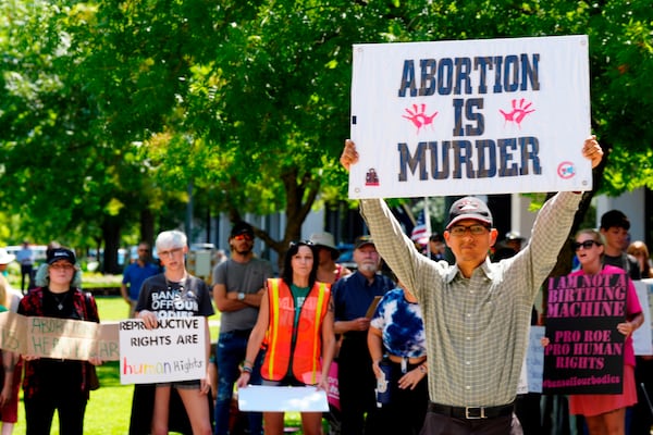 FILE - A man supporting restrictions on abortion holds a sign as abortion-rights supporters hold signs behind him outside the South Carolina Statehouse on Thursday, July 7, 2022, in Columbia, S.C. (AP Photo/Meg Kinnard, file)