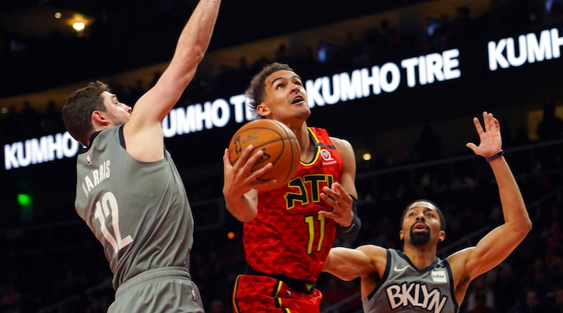 Atlanta Hawks guard Trae Young (11) drives to the basket between Brooklyn Nets forward Joe Harris (12) and Spencer Dinwiddie in the second half of an NBA basketball game Friday, Feb. 28, 2020, in Atlanta. (AP Photo/Tami Chappell)