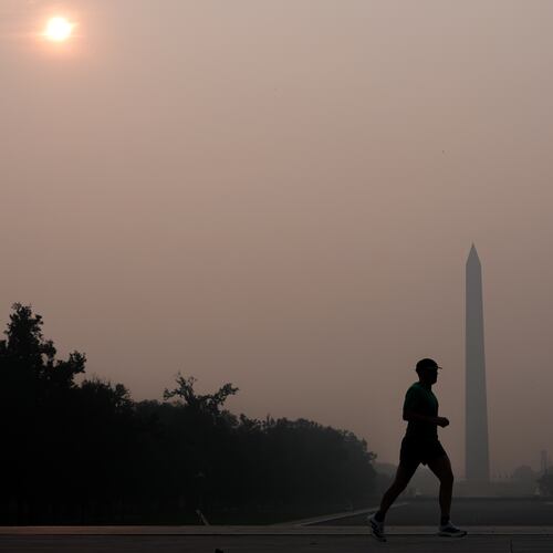The sun is obscured by wildfire smoke as a person runs in front of the Washington Monument and Lincoln Memorial Reflecting Pool, Friday, July 17, 2026, on the National Mall in Washington. (AP Photo/Julia Demaree Nikhinson)