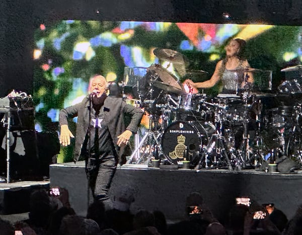 Jim Kerr (front) and drummer Cherisse Osei of Simple Minds perform at Synovus Bank Amphitheater at Chastain Park on Saturday. (Rodney Ho/AJC)