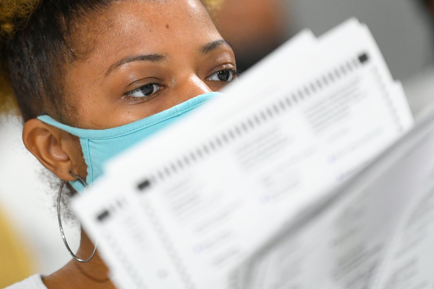 An election worker looks at ballots as votes for President are recounted at the Gwinnett County elections office on Friday, Nov.13, 2020 in Lawrenceville. (JOHN AMIS FOR THE ATLANTA JOURNAL-CONSTITUTION)