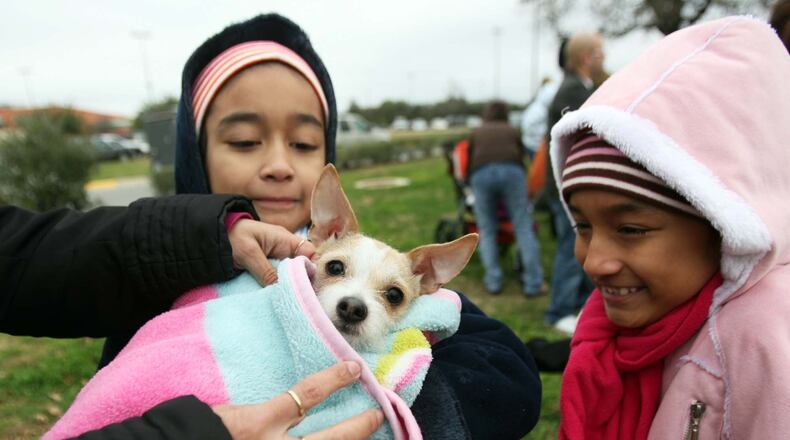 Sisters Marisol and Isabel Vasquez bundle their dog Pebbles in a blanket during a wintertime vaccination drive in 2009.