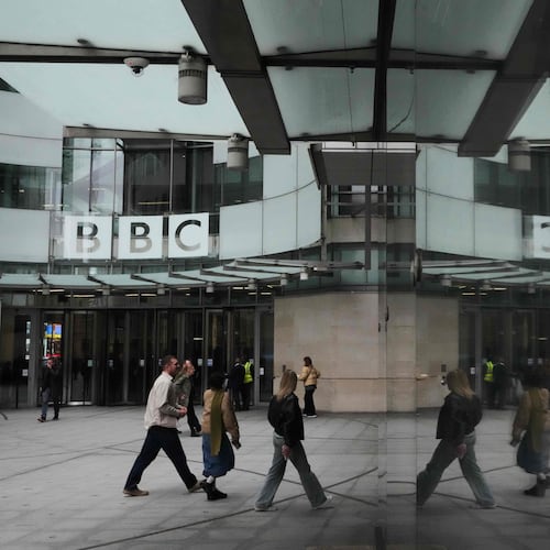 Pedestrians are reflected as they walk outside BBC Broadcasting House in London, Tuesday, Nov. 11, 2025. (AP Photo/Kirsty Wigglesworth)