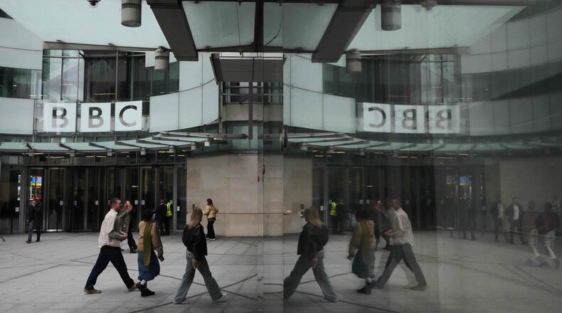 Pedestrians are reflected as they walk outside BBC Broadcasting House in London, Tuesday, Nov. 11, 2025. (AP Photo/Kirsty Wigglesworth)