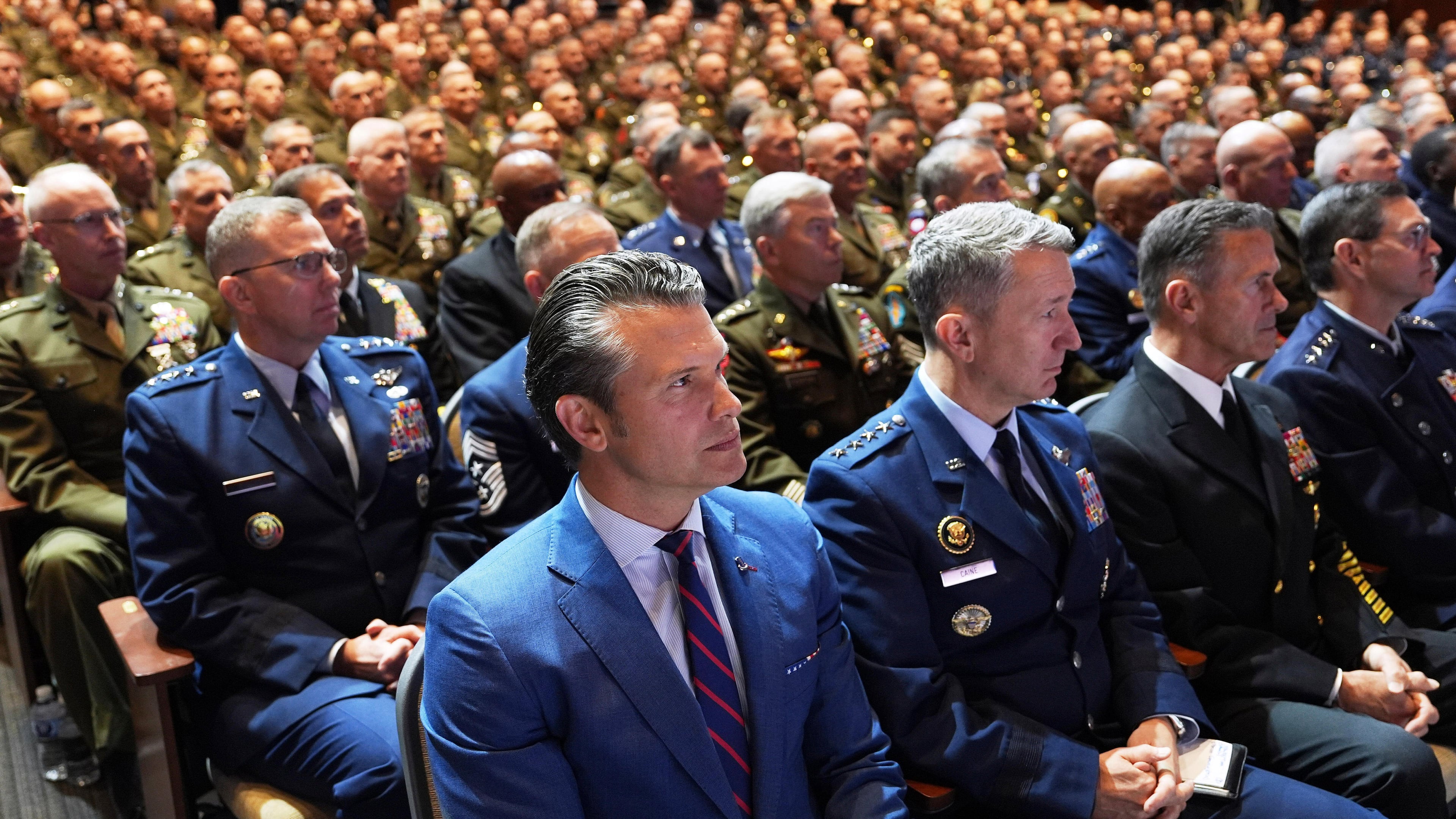 Defense Secretary Pete Hegseth, center, sitting with Chairman of the Joint Chiefs of Staff Air Force Gen. Dan Caine, third from right, and U.S. military senior leadership as they listen to President Donald Trump speaks at Marine Corps Base Quantico, Tuesday, Sept. 30, 2025 in Quantico, Va. (AP Photo/Evan Vucci)