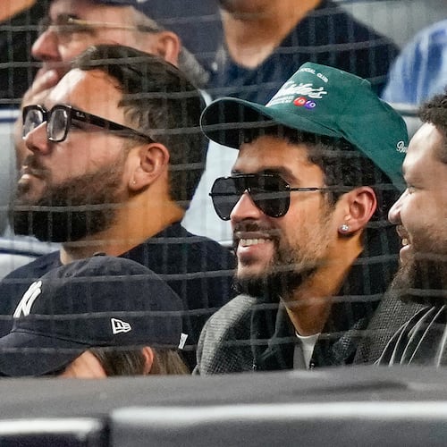 Bad Bunny, center, watches play between the New York Yankees and the Toronto Blue Jays during the second inning of Game 3 of baseball's American League Division Series, Tuesday, Oct. 7, 2025, in New York. (AP Photo/Yuki Iwamura)