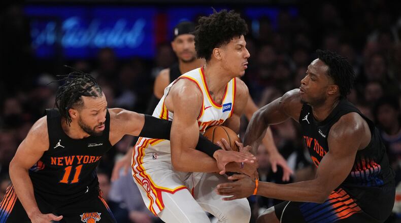 New York Knicks' Jalen Brunson, left, and OG Anunoby, right, defend Atlanta Hawks' Jalen Johnson, center, during the first half in Game 5 of a first-round NBA playoffs basketball series, Tuesday, April 28, 2026, in New York. (AP Photo/Frank Franklin II)