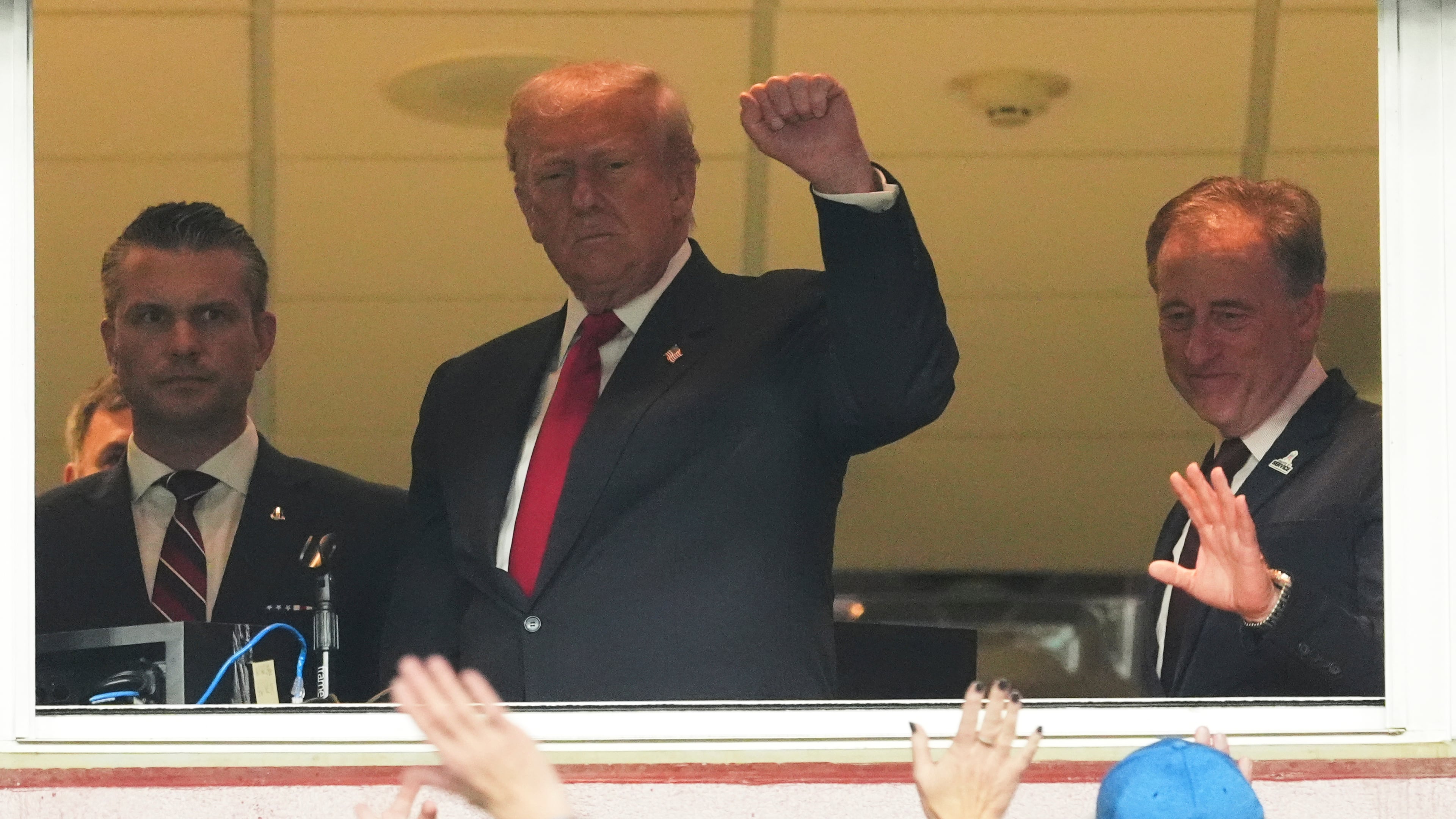 President Donald Trump, center, gestures to the crowd alongside Defense Secretary Pete Hegseth, left, and Washington Commanders owner Josh Harris, as they attend an NFL football game between the Commanders and the Detroit Lions at Northwest Stadium in Landover, Md., Sunday, Nov. 9, 2025. (AP Photo/Jacquelyn Martin)