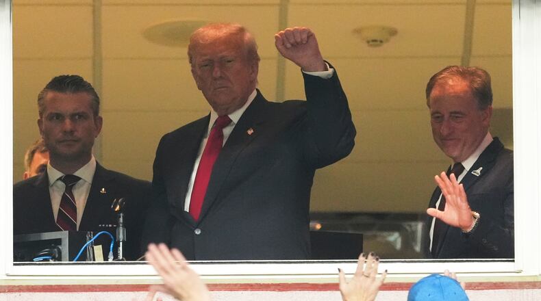 President Donald Trump, center, gestures to the crowd alongside Defense Secretary Pete Hegseth, left, and Washington Commanders owner Josh Harris, as they attend an NFL football game between the Commanders and the Detroit Lions at Northwest Stadium in Landover, Md., Sunday, Nov. 9, 2025. (AP Photo/Jacquelyn Martin)