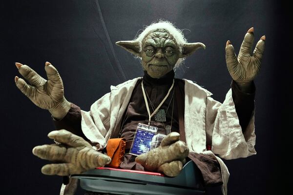 A Star Wars fan dressed as Yoda tries to look airborne during a fan convention called the Star Wars Celebration Japan in Chiba, near Tokyo, Friday, April 18, 2025. (AP Photo/Hiro Komae)