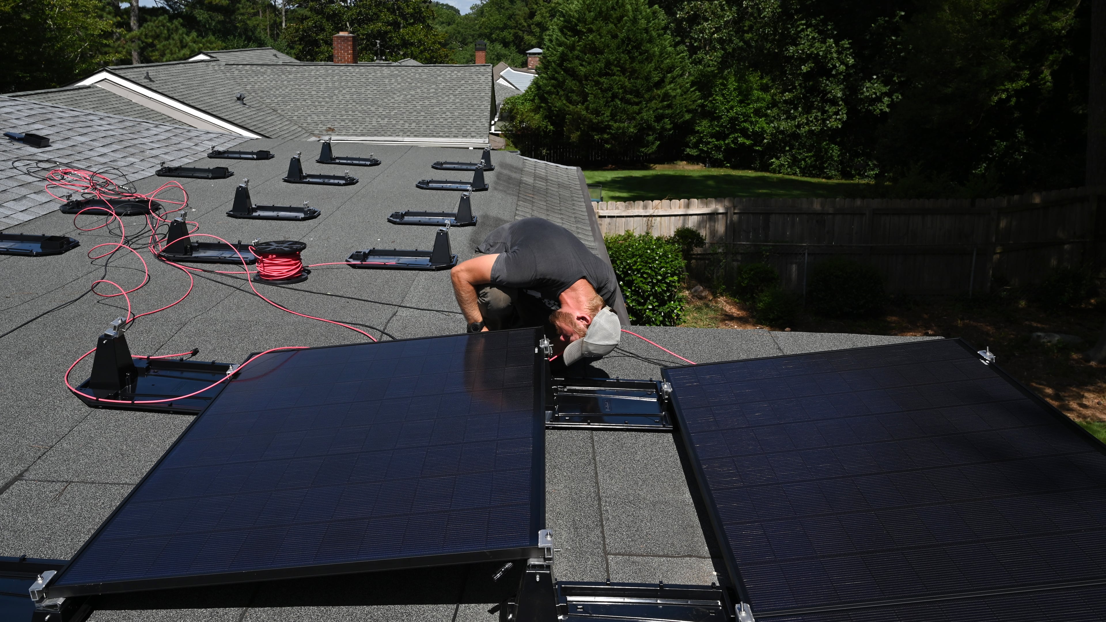 Ryan Johnson with Custom Solar Solutions installs solar panels on a home in Atlanta on Thursday, July 17, 2025. (Hyosub Shin/AJC)