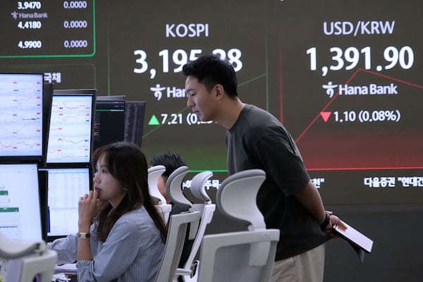 Currency traders watch monitors near a screen showing the Korea Composite Stock Price Index (KOSPI) and the foreign exchange rate between U.S. dollar and South Korean won, right, at the foreign exchange dealing room of the Hana Bank headquarters in Seoul, South Korea, Monday, July 21, 2025. (AP Photo/Ahn Young-joon)